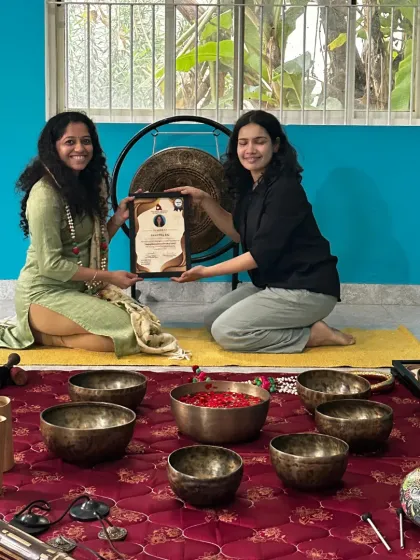 A teacher presents a certificate to a graduate of the sound healing program, marking the successful completion of her training.