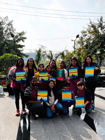 A happy group posing with their sunset paintings after a fun and colorful Sunday workshop.