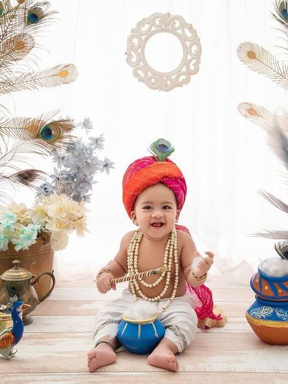 A happy baby Krishna, with his pot of butter and peacock feathers, looking absolutely divine for his festive photoshoot.