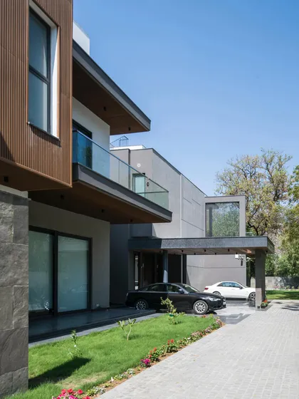 The driveway and entrance of Triveni Farmhouse. The linear volume of the home is a contemporary insertion into the landscape, with tapered details and jutting forms creating a dynamic architectural statement.