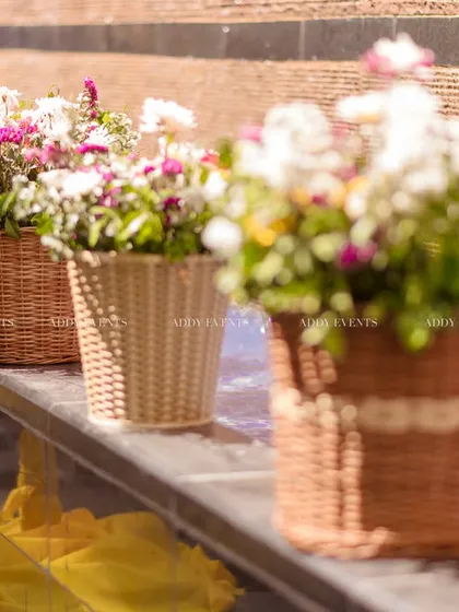A line of wicker baskets filled with fresh flowers, adding a touch of rustic elegance to the poolside decor.