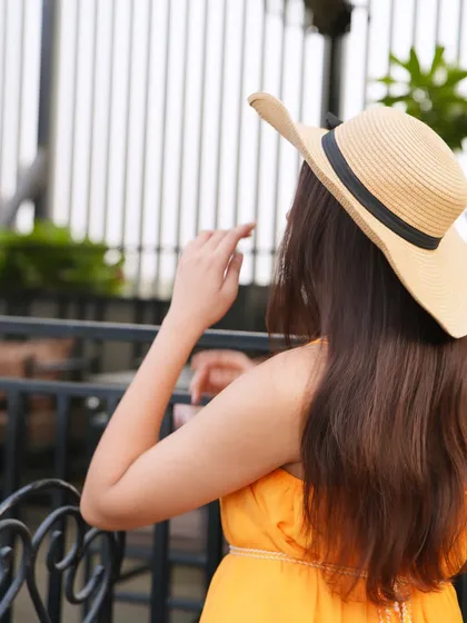 Summer girl mood. A back shot of me in a bright yellow summer dress and a straw hat.