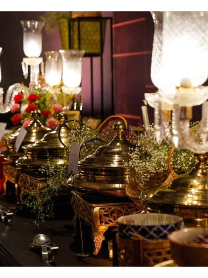 An elegant buffet setup using traditional brass serving dishes and candelabras, blending classic Indian aesthetics with modern buffet service.