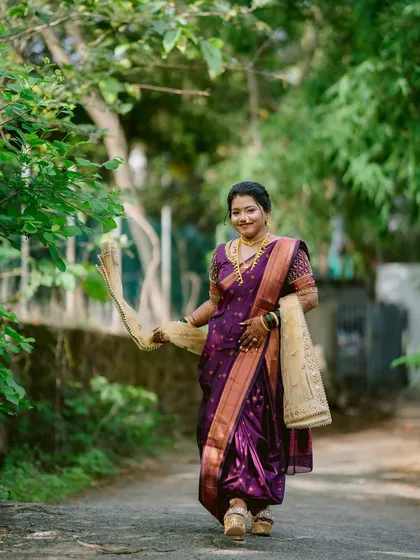 A beautiful Maharashtrian bride in her traditional purple Paithani saree, captured in a serene outdoor setting.