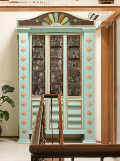 This custom bar cabinet was designed as a centerpiece for a landing. Inspired by Chettinad architecture, it features stained glass panels and a playful colour palette of mint green and ochre, making it a joyful and nostalgic statement piece.