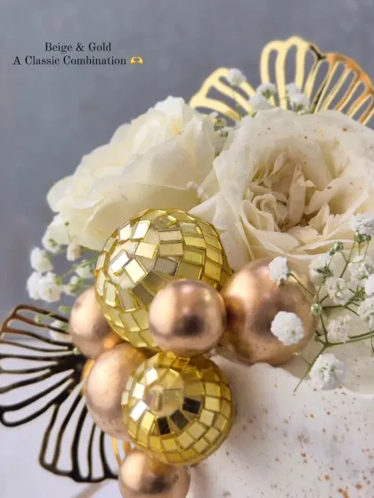 A close-up of the elegant 80th birthday cake, highlighting the fresh flowers and gold disco ball decorations.