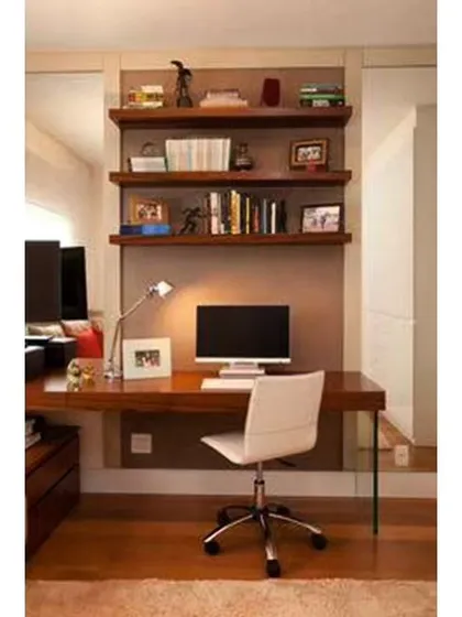 A simple and clean home office design with a wooden desk and floating shelves for books and decor. The use of a mirror on the side wall helps to make the space feel larger and brighter.