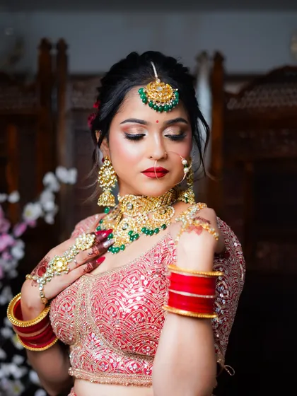 A full-length seated pose showing the entire red lehenga, giving a complete view of the bridal look.