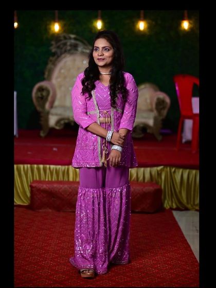 A full view of the purple Chikankari sharara suit. The peplum-style kurta and wide-legged pants create a flattering and fashionable silhouette.