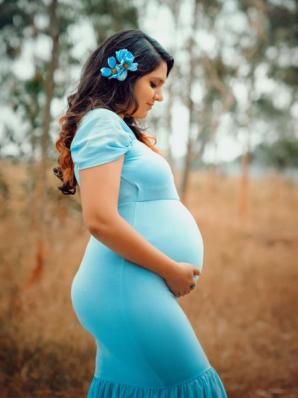 A lovely solo portrait of a mom-to-be enjoying a peaceful moment outdoors. The flower in her hair is a beautiful, simple touch.