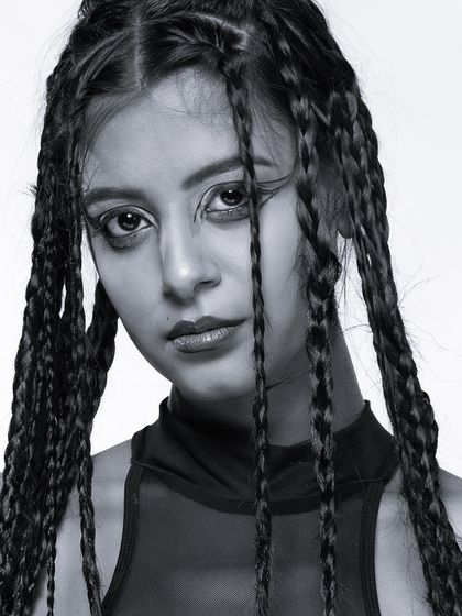 A close-up monochrome portrait with a direct gaze, framed by long braids. This image has a raw, honest feel, perfect for an impactful headshot.