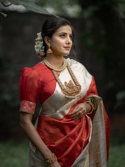 The timeless combination of red and off-white is a favorite for South Indian brides. This Kanchipuram saree, with its rich brocade and elegant puff-sleeved blouse, is a perfect example of classic bridal wear.