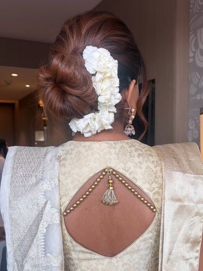 A close-up of a textured bun with fresh white flowers placed along the side. This style is a beautiful option for a sophisticated daytime event or a Christian bride.