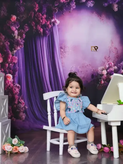 A happy baby girl sits at the piano in a whimsical floral setting. The combination of music and flowers creates a unique and enchanting theme.