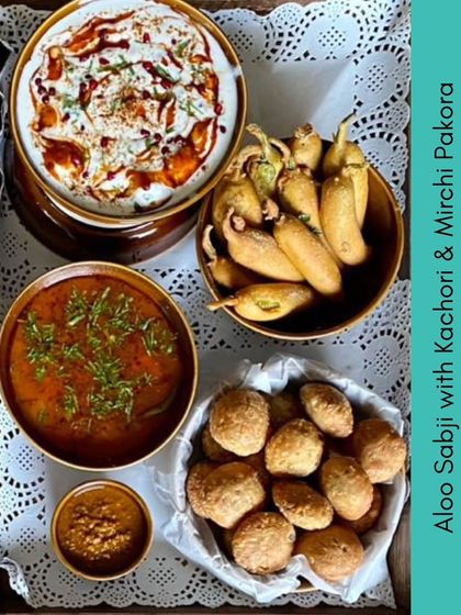 A traditional Indian meal platter featuring Aloo Sabji with Kachori, Mirchi Pakora, and Dahi Bhalla. This is a perfect example of our authentic Purani Dilli summer feast menu.