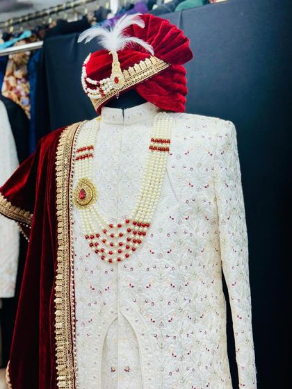 A side view of my floral hand-detailed sherwani. The rich red velvet dupatta with gold trim contrasts beautifully with the ivory fabric, and the custom turban completes the royal aesthetic.