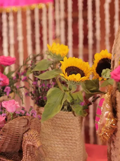 A close-up of sunflowers and pink roses in jute baskets. This combination of rustic textures and bright colors is perfect for a sunlit Mehendi.