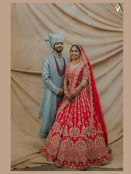 A classic portrait of the bride and groom against a simple backdrop. Their traditional outfits and happy smiles make this a timeless and elegant wedding photograph.