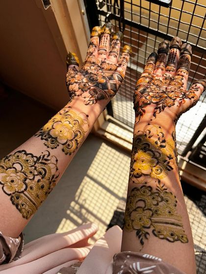 This floral mehendi design extends up the forearms, featuring large, beautifully shaded flowers. The natural light in this photo highlights the fresh, expertly applied henna paste.