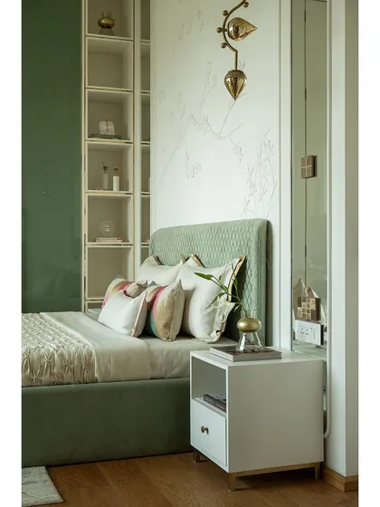A detail shot of the bedside in the green bedroom. The custom light fixture and the open shelving provide both functional storage and a place to display personal treasures.