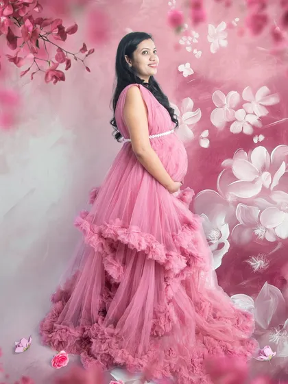 An artistic portrait with a painted floral background. The soft pinks of the gown and the flowers blend together to create a dreamy, watercolor-like effect.