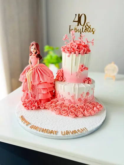 Celebrating 40 with elegance and charm. This cake features a beautiful handcrafted doll in a flowing pink gown, seated next to a two-tier cake adorned with matching pink roses.
