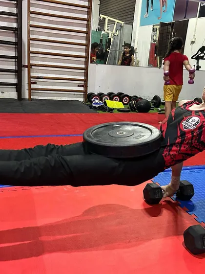 A young athlete builds core and tricep strength with a weighted plank hold on dumbbells. We incorporate resistance training to accelerate strength gains.