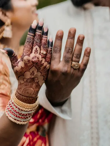A playful shot of the couple's hands, showing the contrast between the henna-adorned hand and the groom's.