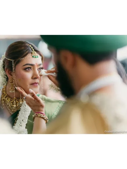 An emotional moment during a South Indian wedding ceremony, as the groom gently wipes a tear from the bride's eye.