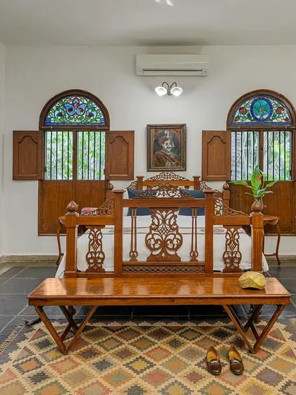 A wider view of the Vasishta suite, showcasing the spacious layout, antique vanity, and beautiful stained-glass windows that let in dappled light.