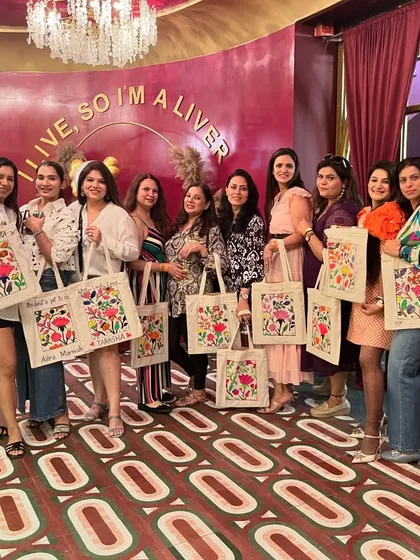 A group of stylish ladies showing off the floral tote bags they painted at a workshop. This is a perfect activity for a fun and fashionable get-together.