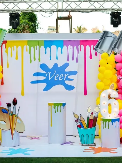 The full backdrop for the art party, featuring a vibrant paint-drip design, giant paint buckets, and art palette props.