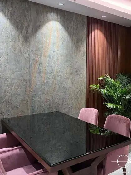 A dining space that combines textures and colors, with soft pink velvet chairs, a glossy black table, and a textured stone wall. This design shows our skill in creating layered and interesting interiors.