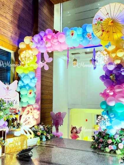 An enchanting entrance for a fairy and butterfly themed party. The arch is decorated with a rainbow of pastel balloons, butterfly cutouts, and a Japanese-style umbrella, creating a unique and whimsical welcome.