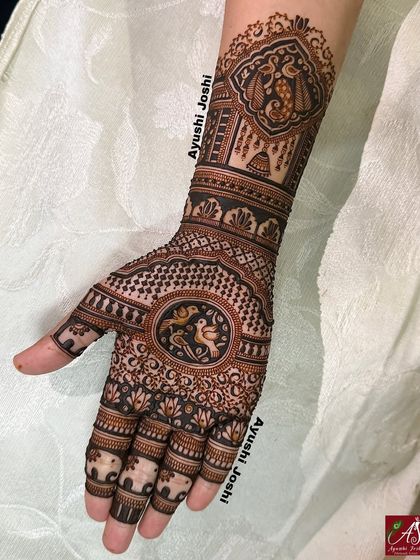 An elegant Roka ceremony mehendi featuring love birds at the center of the palm, with a peacock and jhumka design on the wrist.