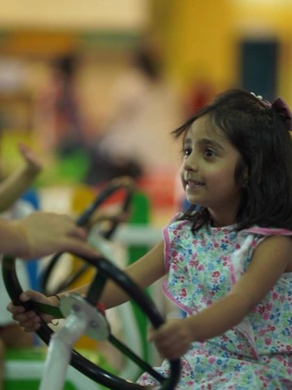 This little girl is all smiles as she takes the wheel on our mini merry-go-round. It's one of our many gentle rides perfect for younger children to enjoy.