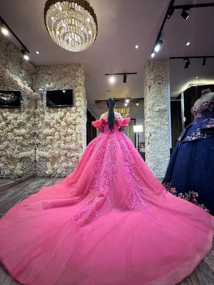 The back view of our rose pink ball gown, showcasing its magnificent trail and the detailed embroidery that continues down the length of the skirt. The corset back ensures a flattering and secure fit.