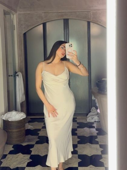 A mirror selfie in a gorgeous bathroom, wearing a simple yet elegant white satin slip dress.