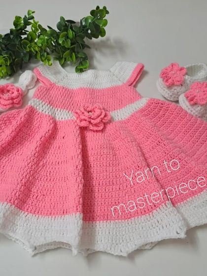 Styled with a touch of greenery, this image showcases the craftsmanship of the pink floral frock set, from the scalloped white trim to the flower accents.