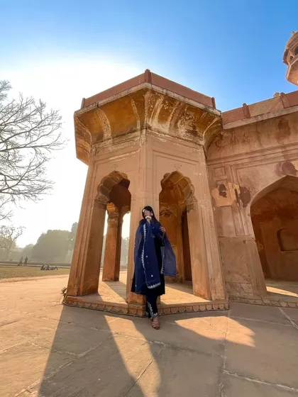 Using the morning sun and grand architecture to create a dramatic silhouette. This wide-angle shot captures the grandeur of the location and the elegance of the traditional blue suit.
