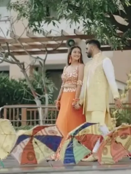 The couple sharing a moment during their Haldi ceremony, with colorful umbrellas in the foreground adding to the festive feel.