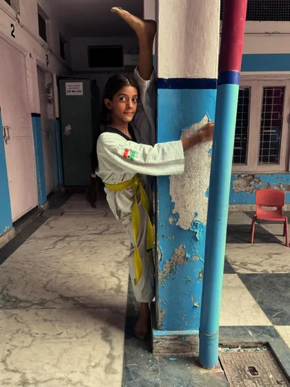 The determination in her eyes says it all. A young student holds a difficult wall split, proving her strength and flexibility.