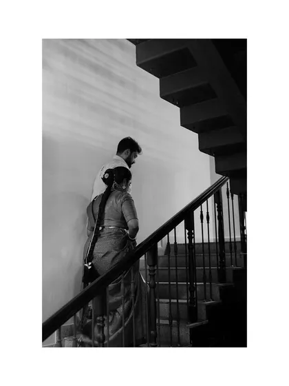 A quiet, artistic moment of Nivetha and Dipak walking up the stairs together during their wedding day. This black and white shot captures a simple, shared journey.