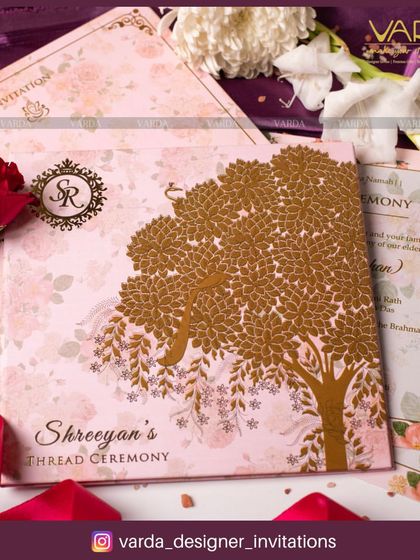 A sophisticated invitation for a thread ceremony, featuring a delicate pink floral background and a striking gold foil tree of life. The design includes a custom monogram, adding a personalized and luxurious touch to this sacred event.