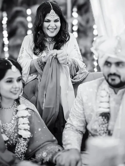 A candid moment of a family member's joyful participation in a wedding ritual. Black and white brings out the raw emotion and happiness in her expression.