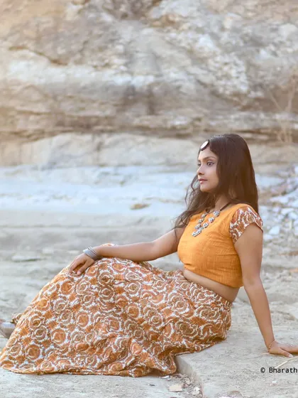 A seated portrait in the bohemian-style outfit. The relaxed pose and natural background make this feel like a lifestyle fashion shot.