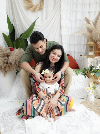 A sweet family photo where the focus is on the baby girl, with her parents framing her with love and smiles.