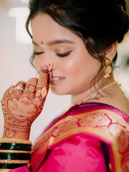 A detailed shot focusing on the bride's intricate henna and traditional nose ring (nath).
