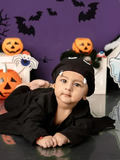 A cute baby bat lying down amongst the pumpkins and ghosts. This pose is great for younger babies during our Halloween sessions.