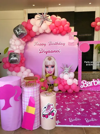 A full view of the pink Barbie theme for Diyaanvi's birthday. The setup is complete with a themed floor mat and a Barbie photo booth frame.
